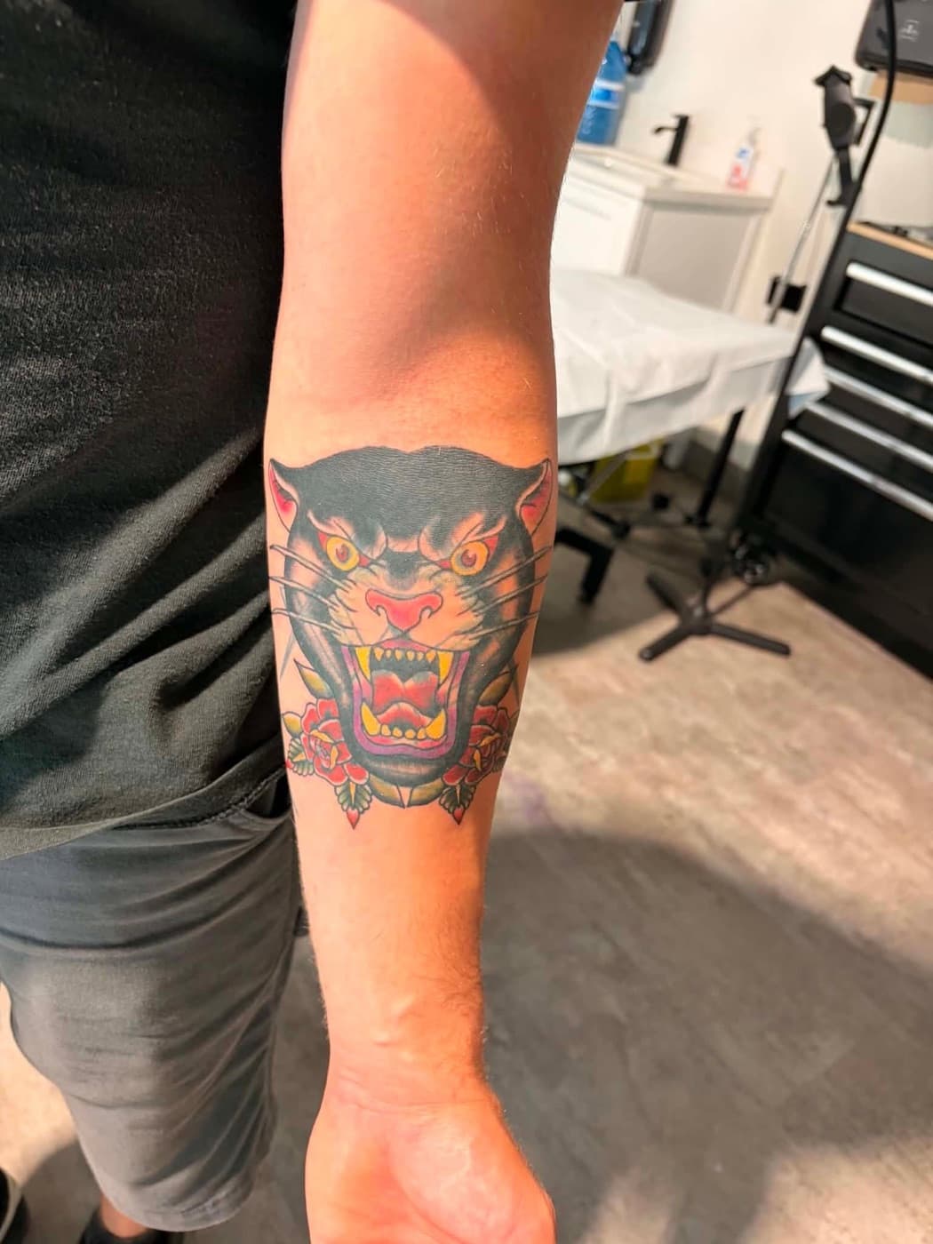 Traditional panther head with roses, bold colour on a forearm