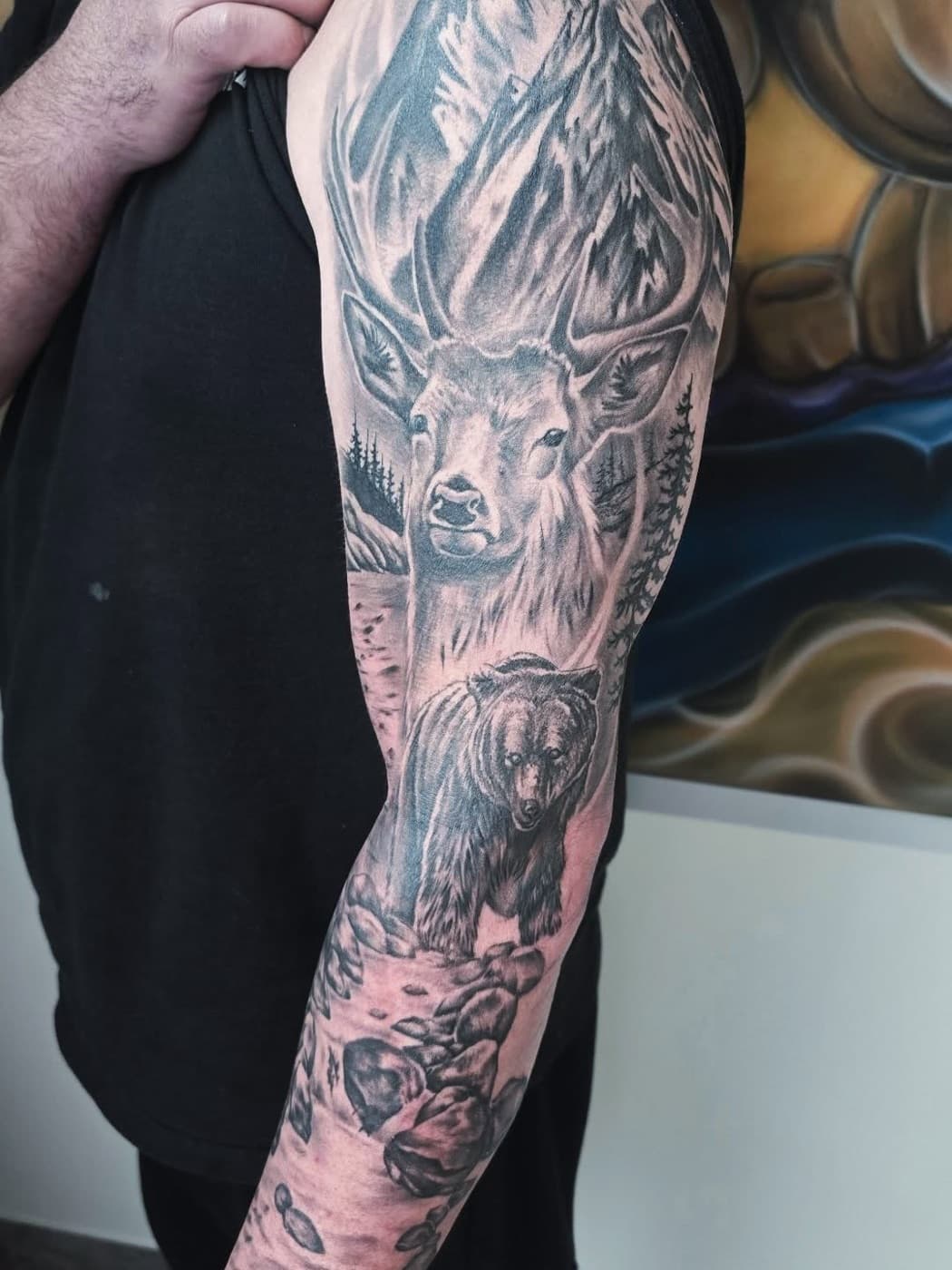 Full sleeve: an elk below mountains and pines, a grizzly bear and a riverbed beneath it