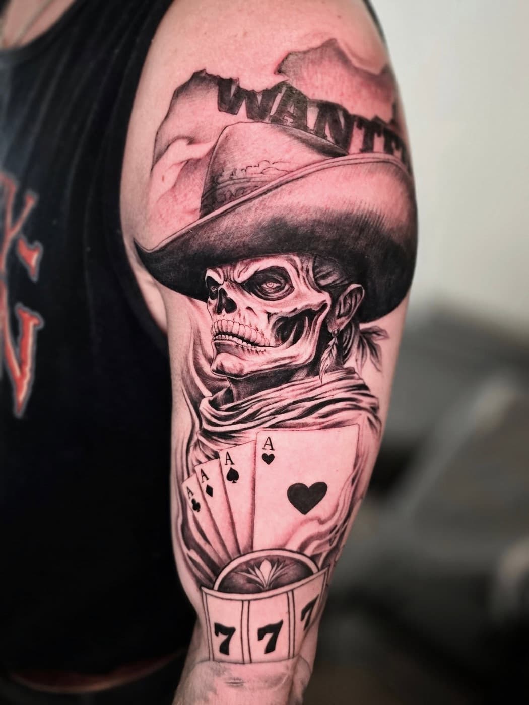 Skull in a wide-brimmed hat above four aces and a slot machine, “wanted” lettering across the shoulder