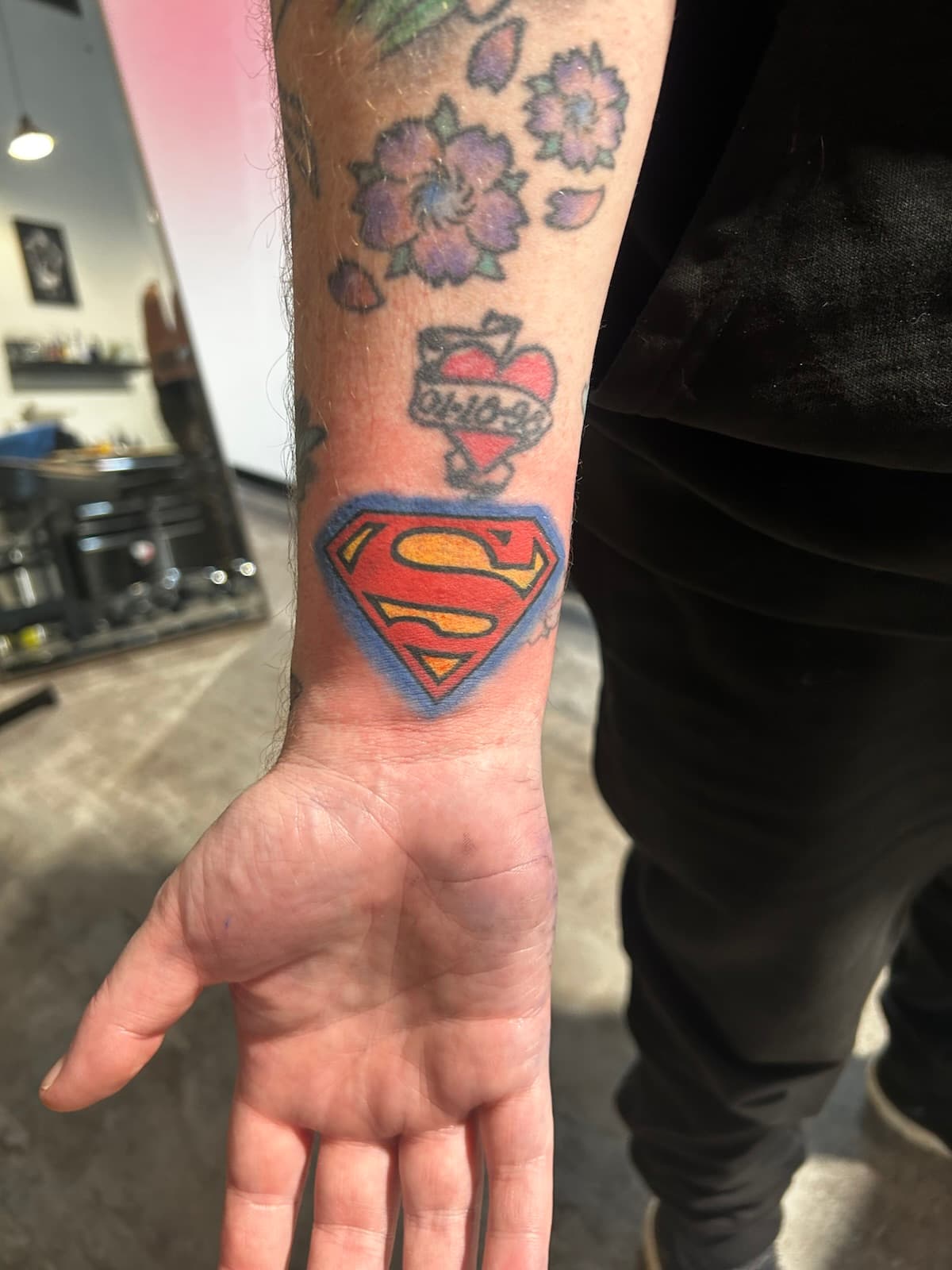 Superman shield in red and yellow with a blue outline, on the inner wrist