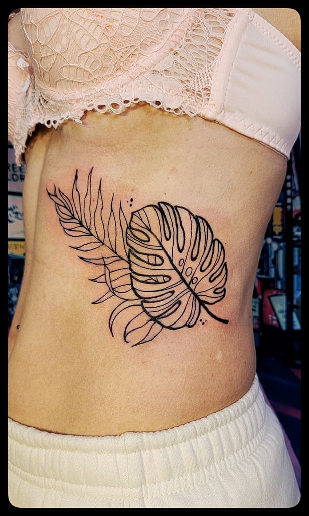 Monstera leaf over a palm frond, black linework on the side of the ribs