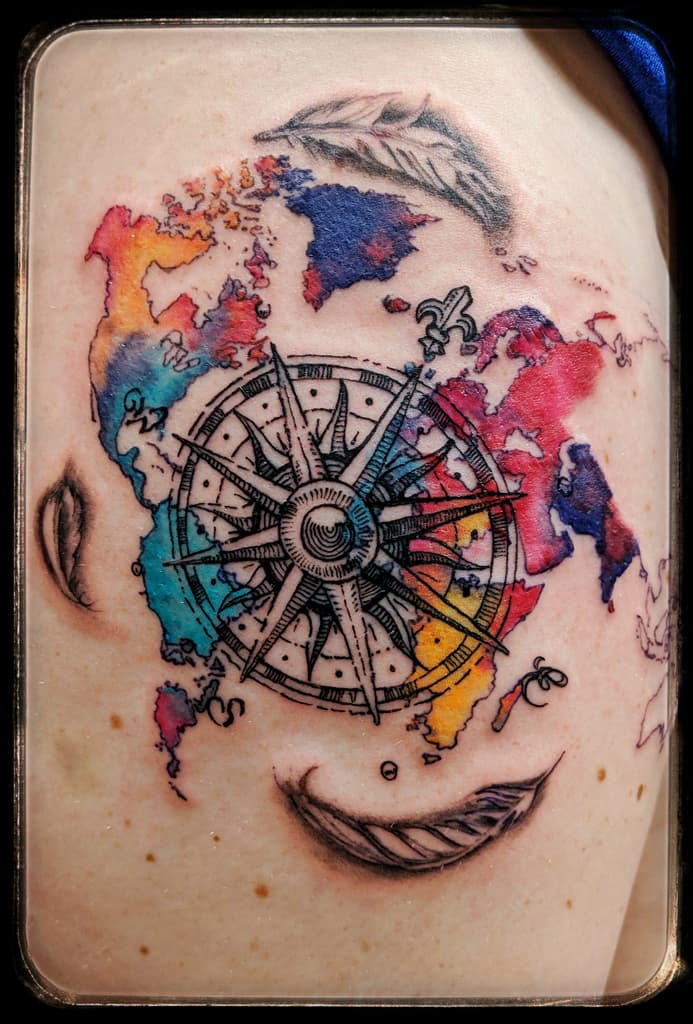 Compass rose over a watercolour world map with black and grey feathers around it
