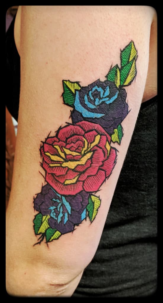 Red rose between two purple and blue roses with green leaves, woodcut-style colour on the back of the upper arm