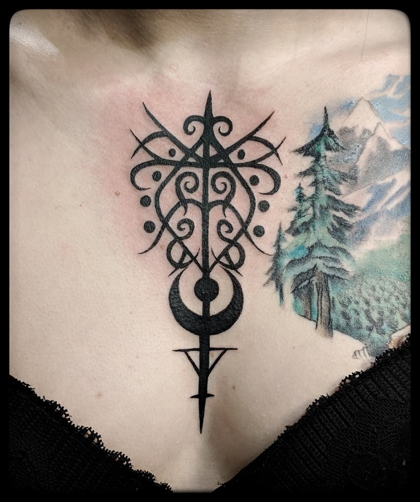 Symmetrical sigil of scrolls, dots and a crescent moon on a vertical staff, solid blackwork on the centre of the chest