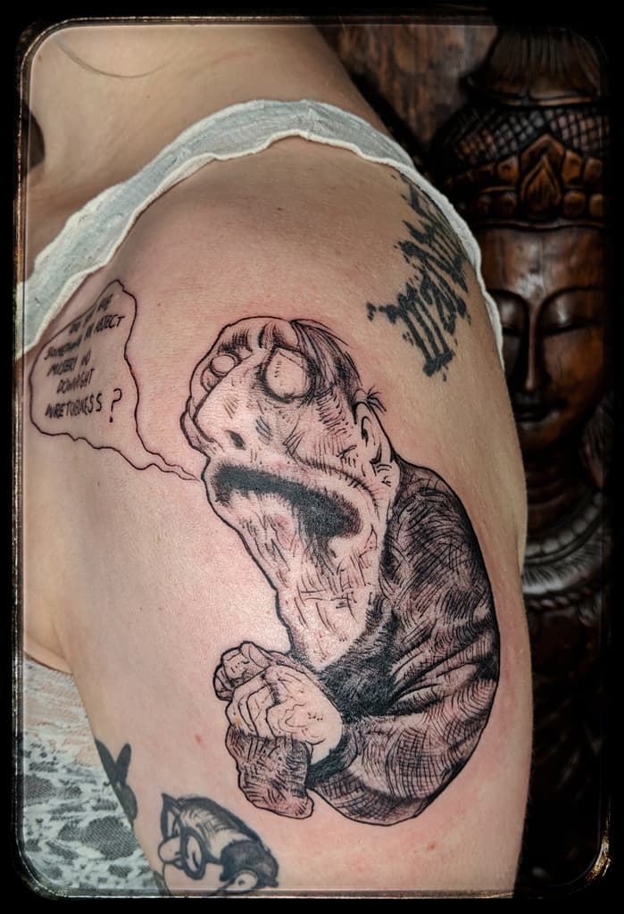 Hunched wrinkled creature with a bulging eye and clasped hands beside a hand-lettered speech bubble, black and grey on the shoulder
