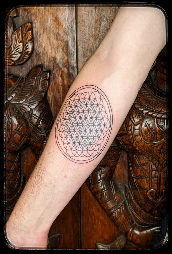 Geometric overlapping-circle pattern inside a double oval outline, fine black linework on the inner forearm