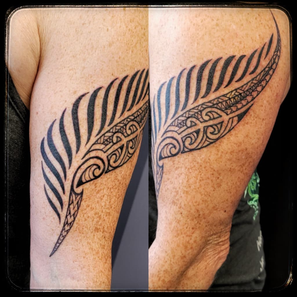 Fern frond filled with Polynesian-style curls and pattern bands, black linework on the back of the upper arm