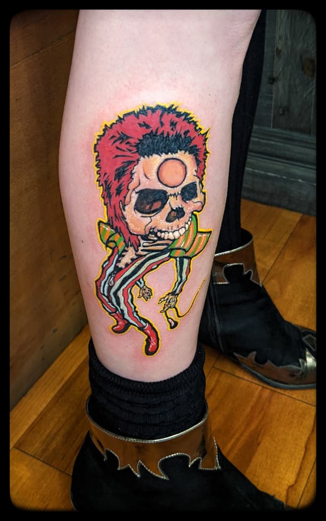 Skeleton with spiky red hair, a round forehead mark and a striped suit, colour on the calf