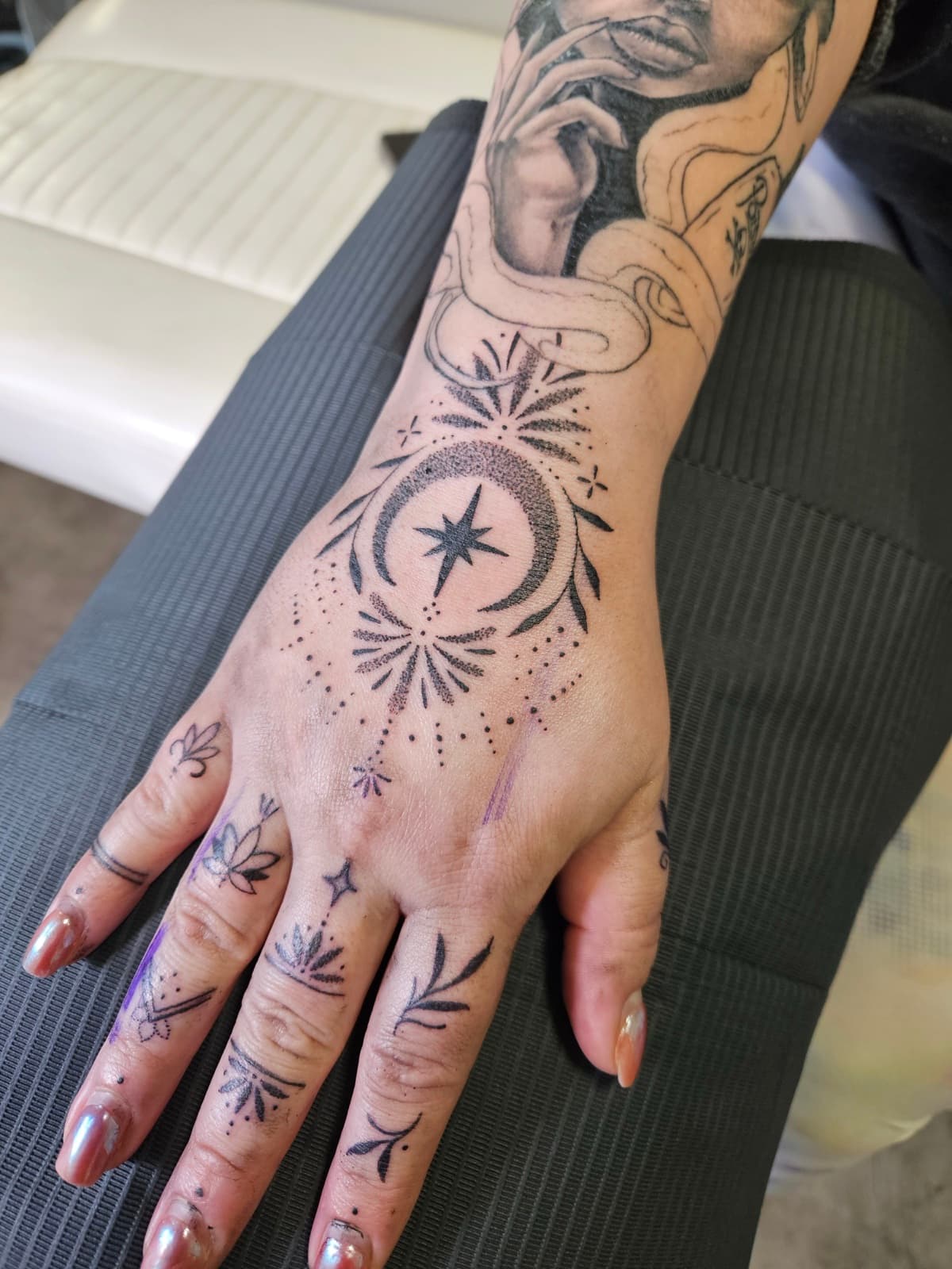Crescent moon and eight-point star framed by dotwork leaves, with ornaments on each finger, hand piece