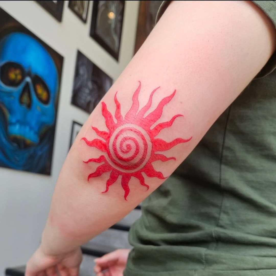 Red spiral sun with flame-like rays on the elbow