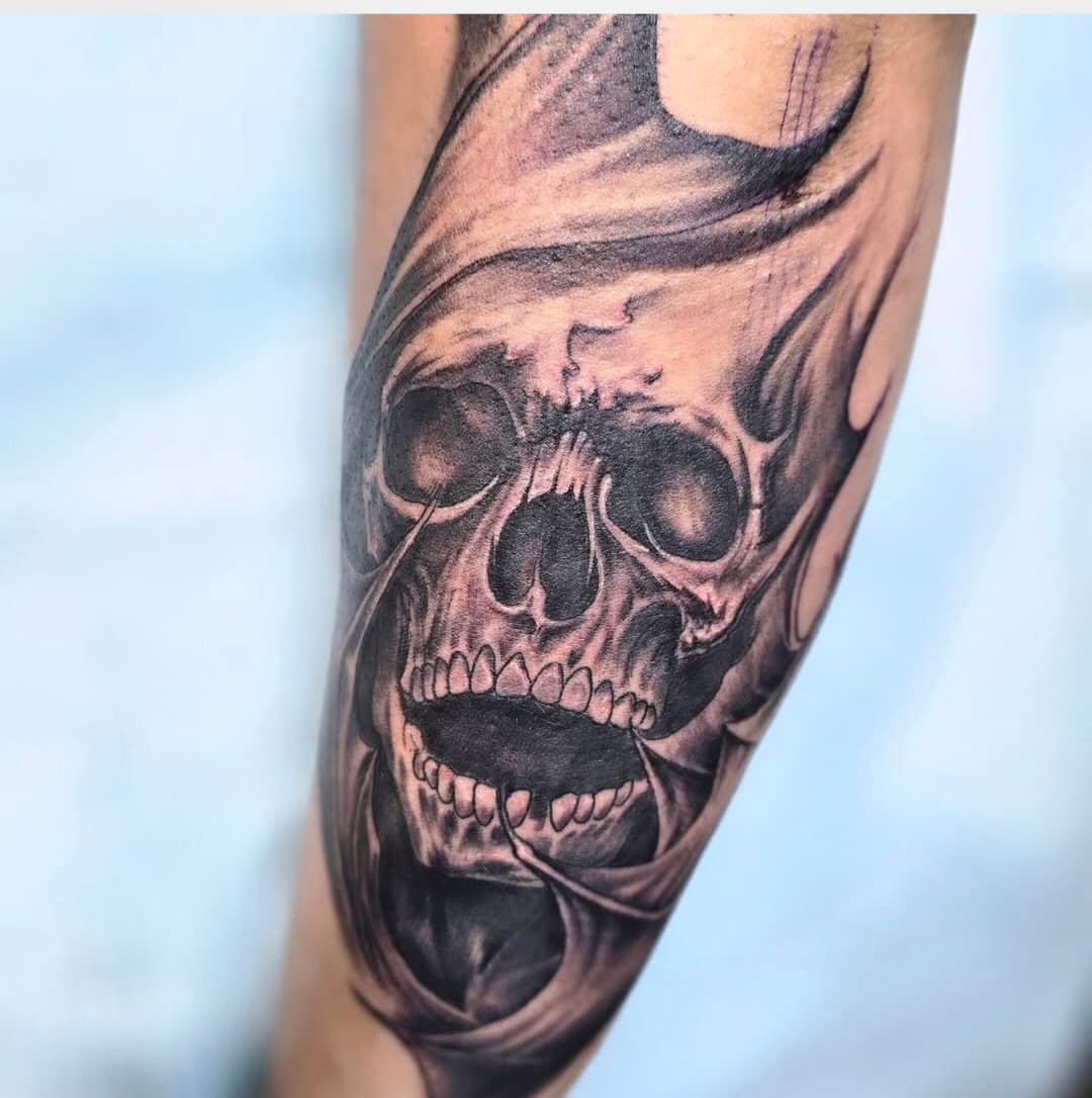 Skull wrapped in flowing smoke, black and grey on the arm